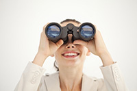 Business woman using binoculars - Peter Barron Stark Companies