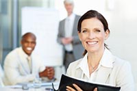 Smiling woman standing in front of two blurred figures in the background