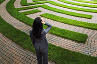 Confused business woman standing in front of maze
